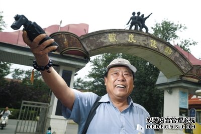 北京電影廠外，趙士軒用閃光燈打亮自己。平時，他都坐在這里等待演戲機會。趙士軒曾是一名法官，退休后為圓演戲夢，成為北影廠門口的一名群演。